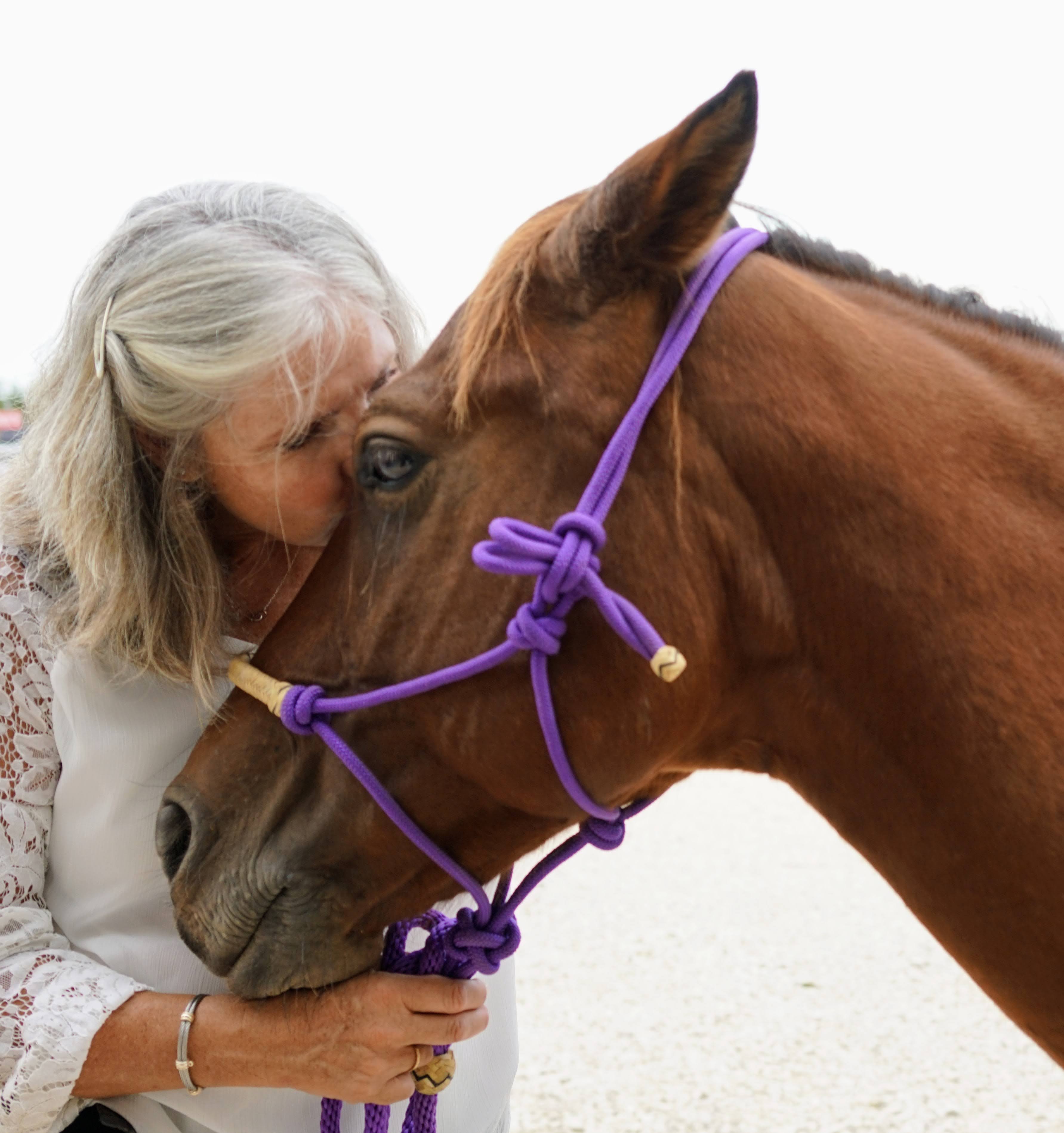 A woman sharing a tender moment with her horse — a kiss that speaks to the bond between humans and animals